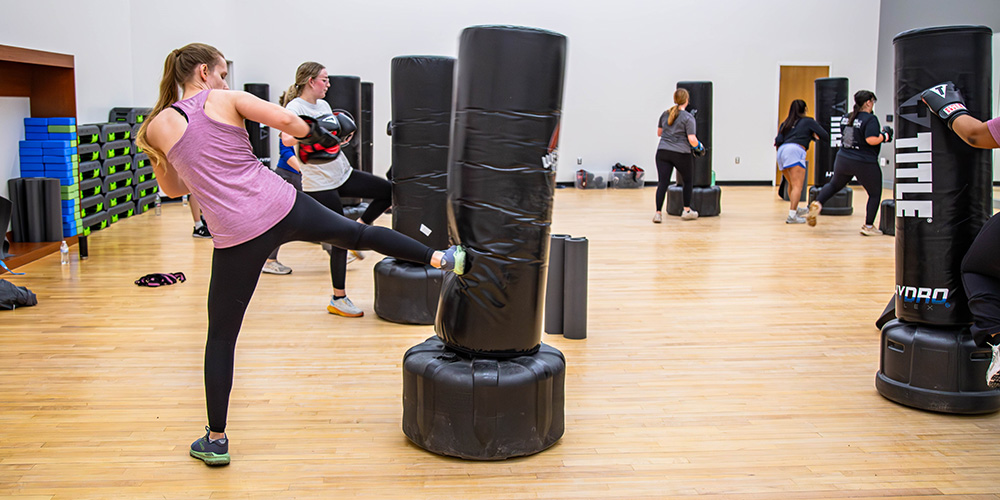 girl kicking her right leg into a standalone punching bag
